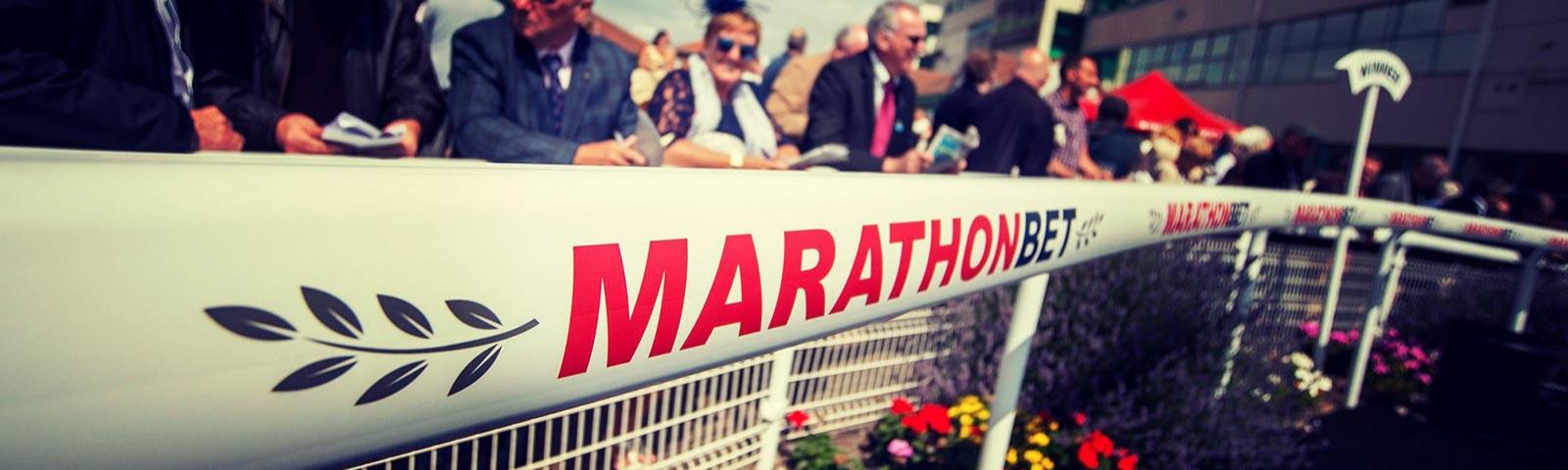 A crowd at Brighton Racecourse behind sponsorship boarding.
