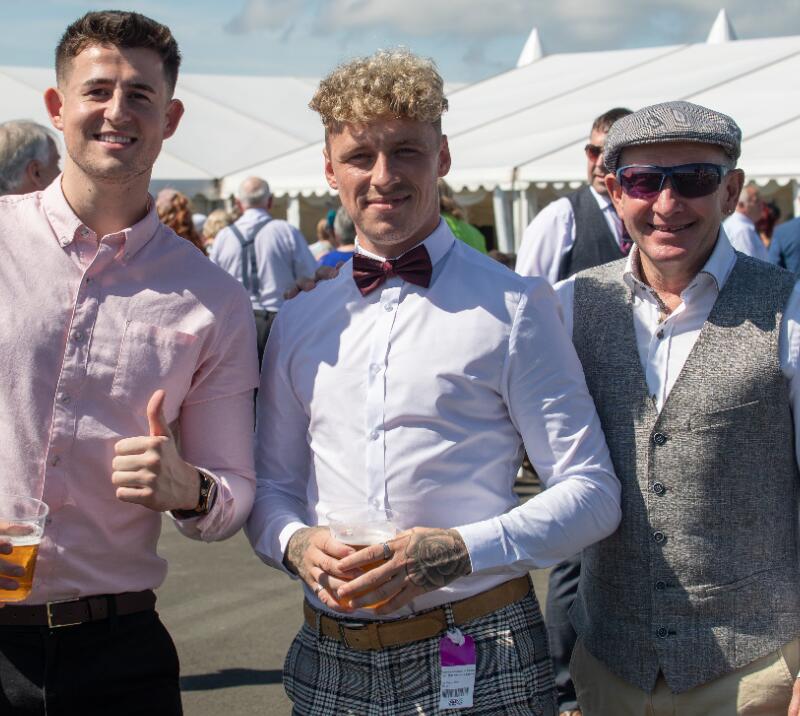 A small, smartly dressed group pose for the camera at the races
