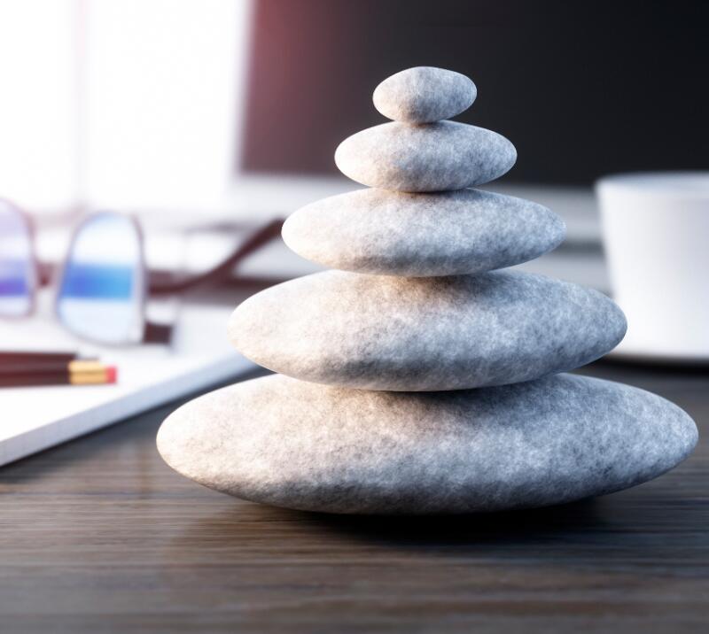 relaxation/wellness stones, on a desk with notepad, glasses, pens, pencils and cup
