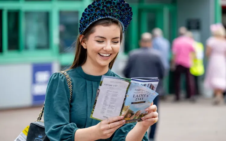 A race goer at Brighton studying the racecard