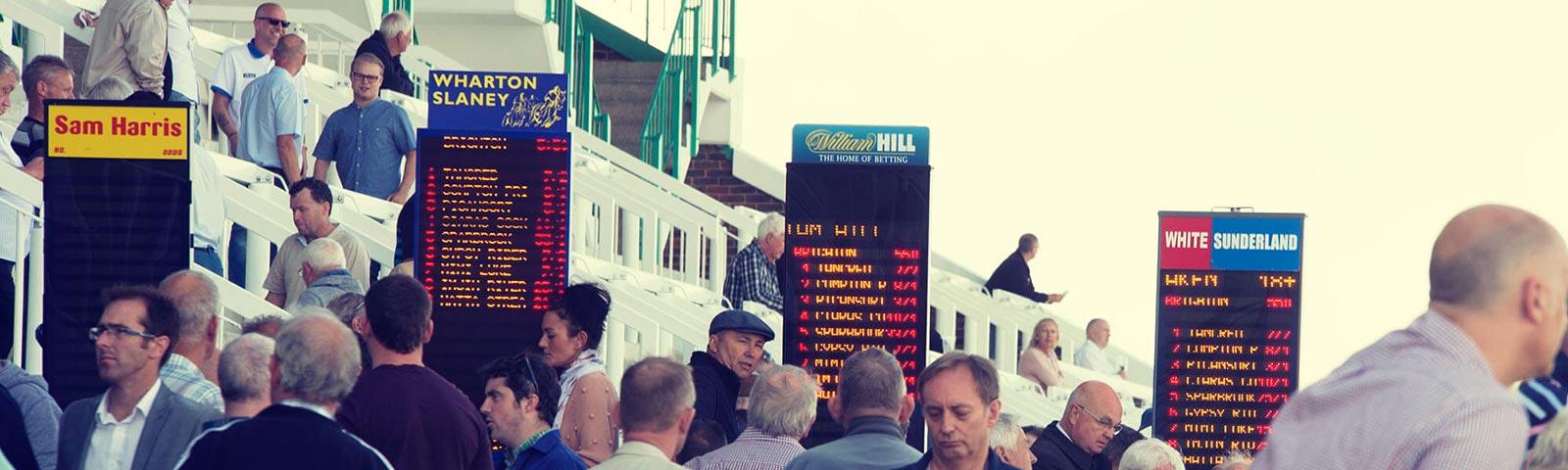 Crowds gathered around bookmakers stands at Brighton Racecourse.